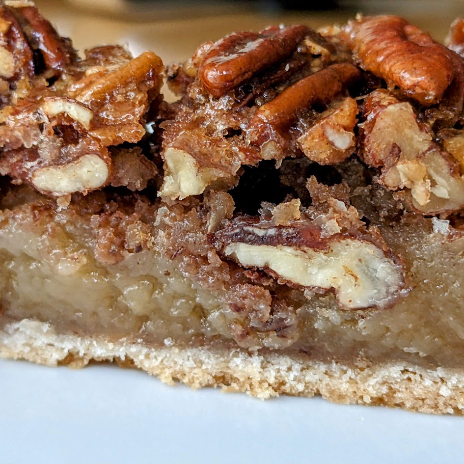 Side view of a slice of Costco pecan pie from the Kirkland bakery, showing the layers of nuts and custard and crust.