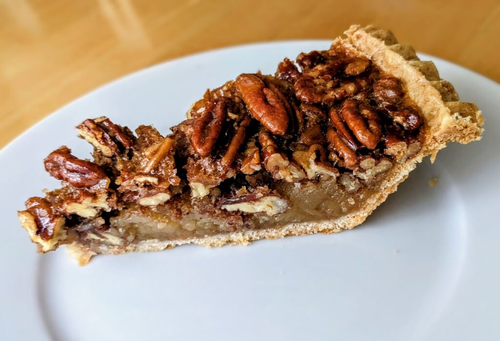 A slice of Costco pecan pie sitting on a small white plate.