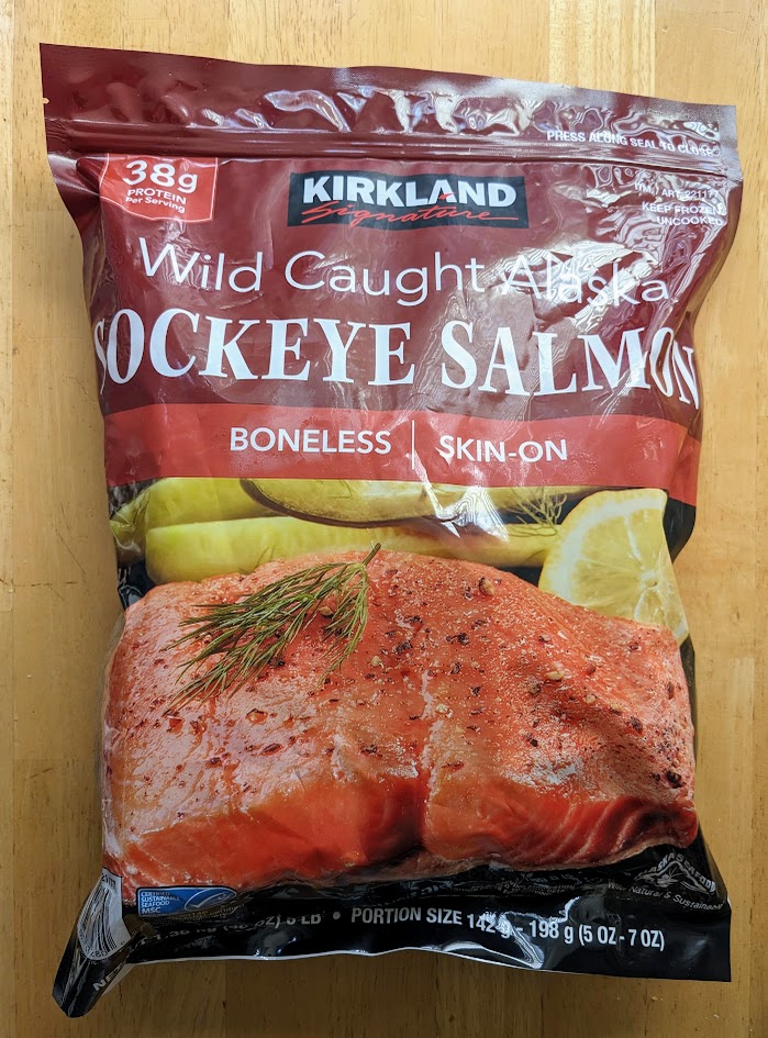 A bag of frozen Kirkland Wild-Caught Sockeye Salmon from Costco, sitting on a wooden table.