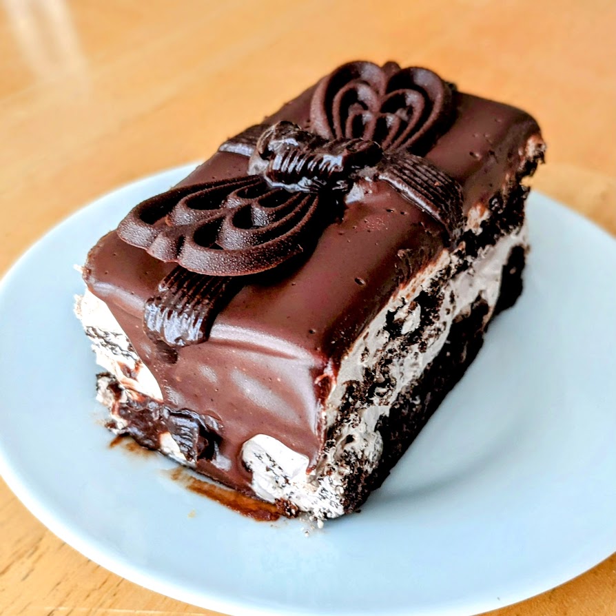 A slice of chocolate ganache supreme cake sitting on a white plate, from the Publix Bakery.