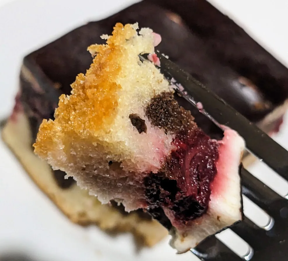 A forkful of Donauwelle cake by Aldi, showing the layers of golden cake, morello cherries, cream, and chocolate.