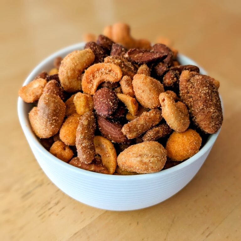 A small white bowl filled with Costco Sweet Heat Snack Mix, sitting on a white table.