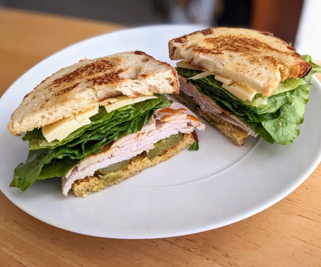 A toasted club sandwich made with Costco Oven Browned Turkey Breast on a white plate.