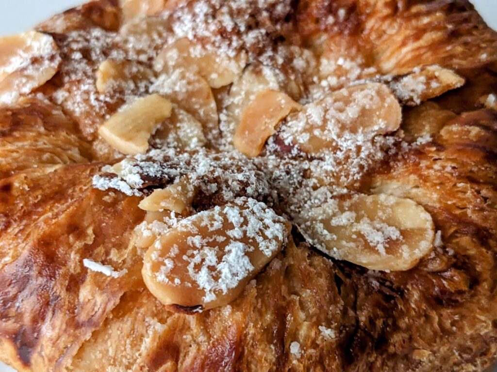 Nut slices and powdered sugar garnish on top of an Almond Croissant from Costco.