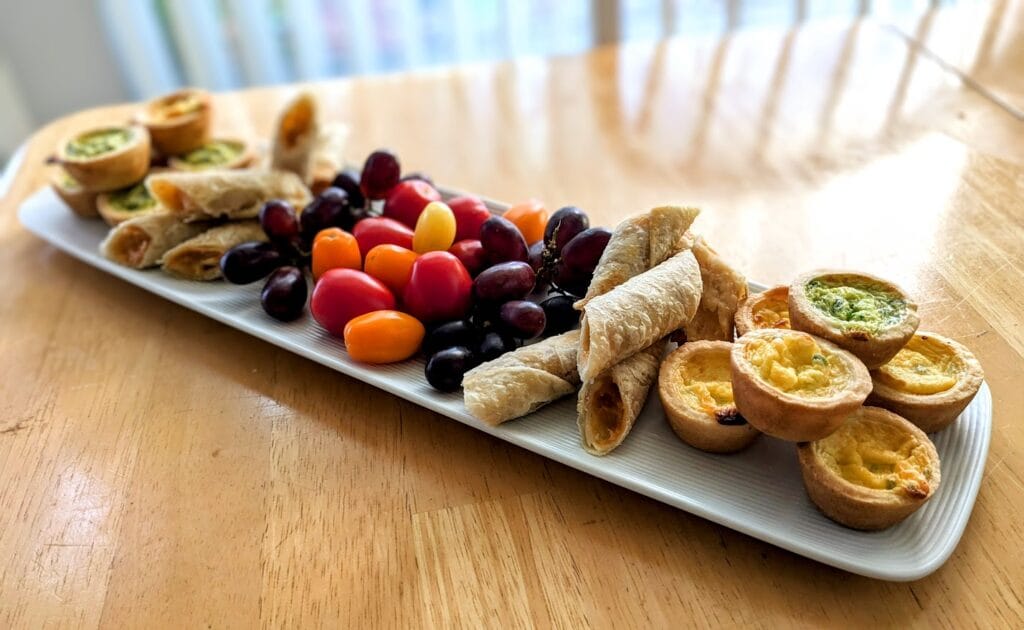 A long white tray of appetizers, including mini quiches from Cuisine Adventures.