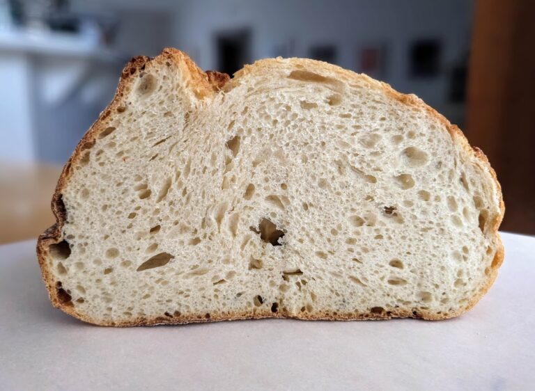 A cross-section of a loaf of Costco Rustic Italian Loaf, sitting on white parchment paper.