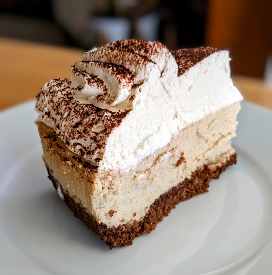 A slice of Costco Tiramisu Cheesecake on a white dessert plate.