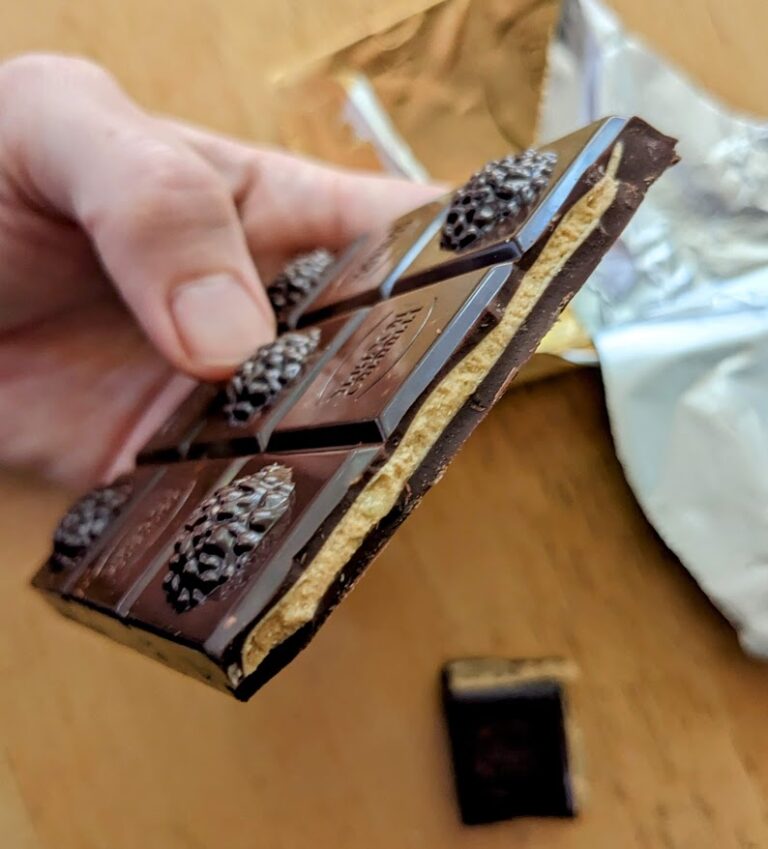 A hand holding a bar of Ferrero Rocher Dark Hazelnut Crunchy Salted Caramel Chocolate.
