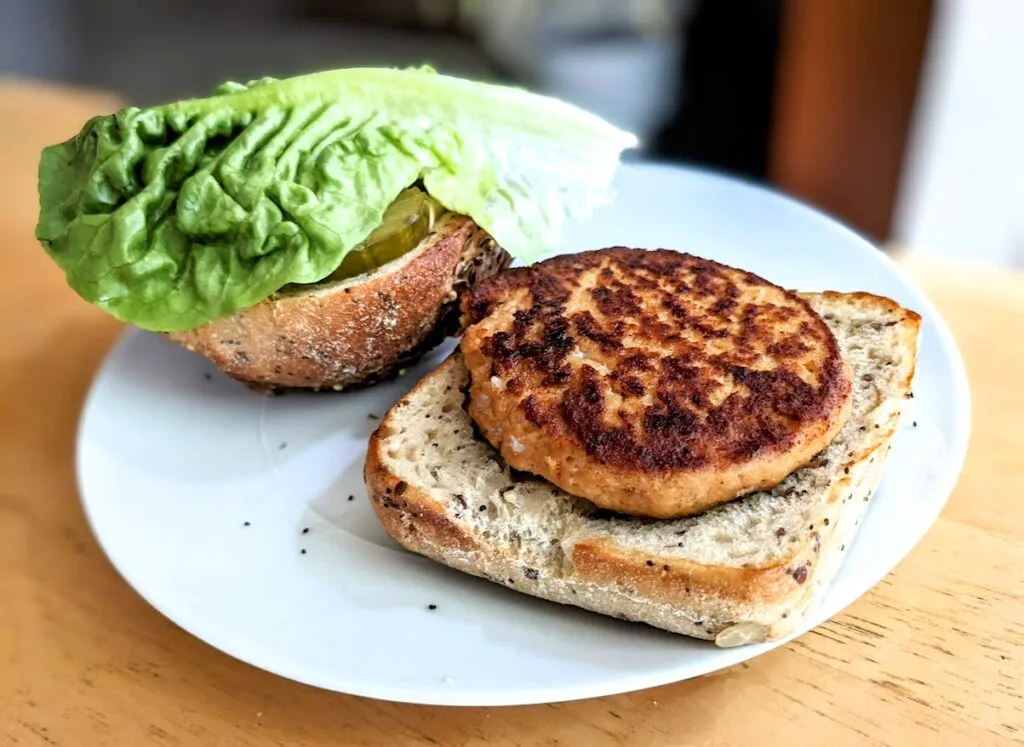 A white plate with an open bun and a Fremont chipotle salmon burger from Aldi.
