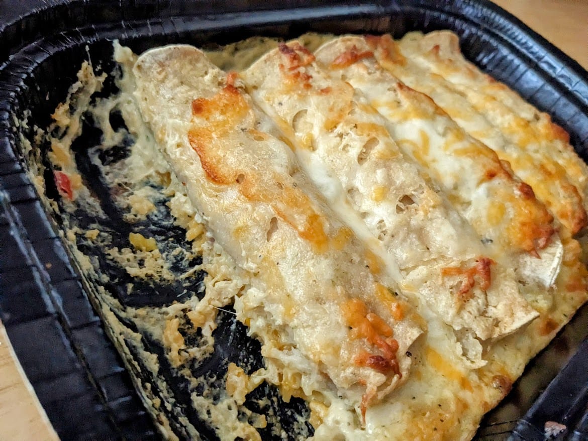 Side view of a tray of Chef Gustavo Chicken and Cheese Enchiladas, showing the tiny amount of rice underneath.