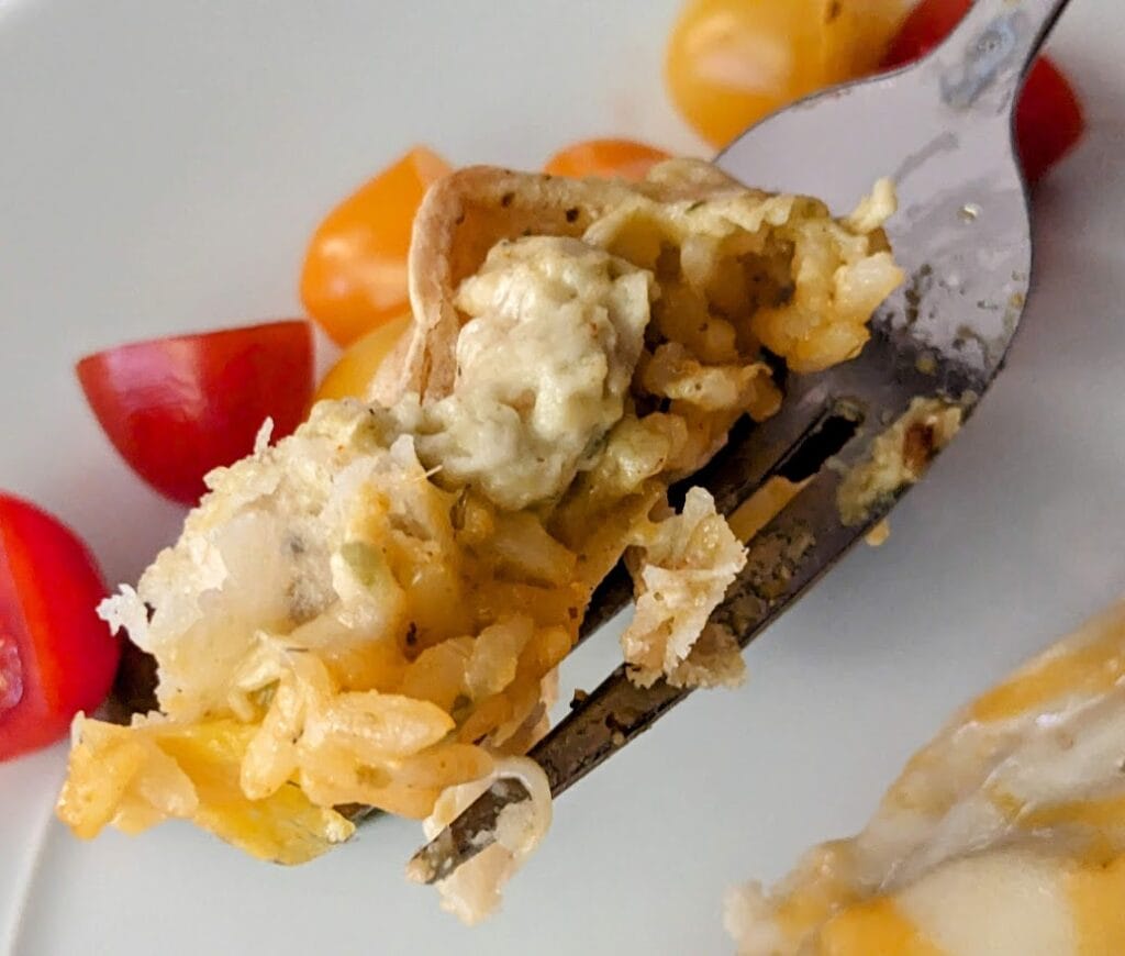 A fork with a bite of enchilada in hatch chile crema sauce from Chef Gustavo.