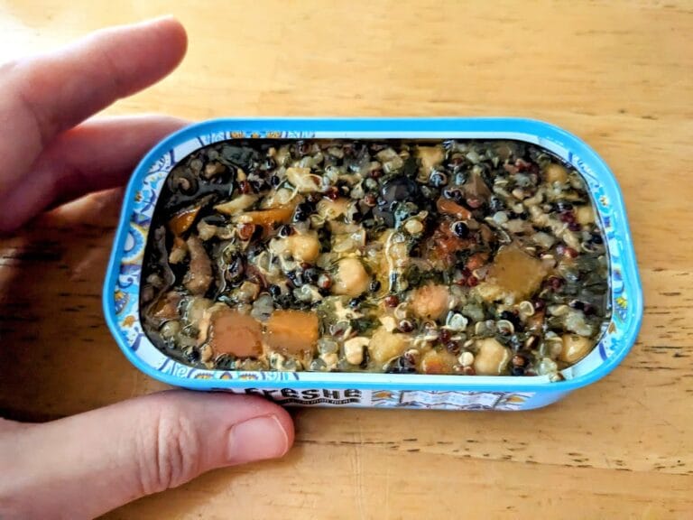 A hand holding a blue can of Freshe Salmon Moroccan Tagine, with the lid removed.