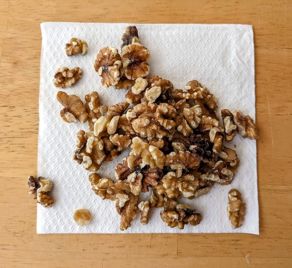 A white napkin with a pile of walnut halves and pieces from Costco.