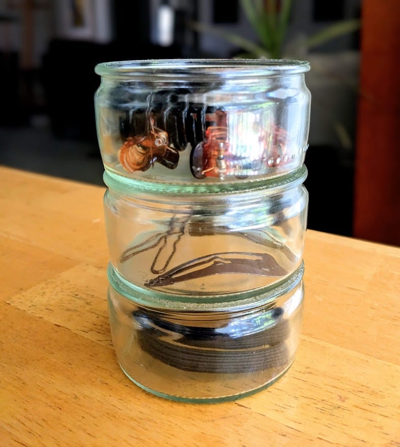 Three empty Senoble French Creme Brulee jars stacked with hair accessories inside.