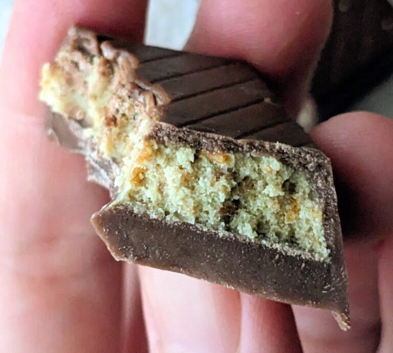 Fingers holding a bitten Dubai Milk Chocolate Bar from Nutty Fruity.