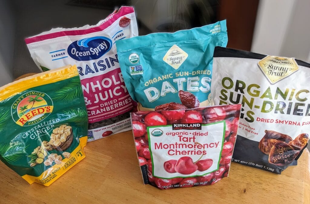 Plastic bags of assorted dried fruits from Costco sitting on a kitchen table.