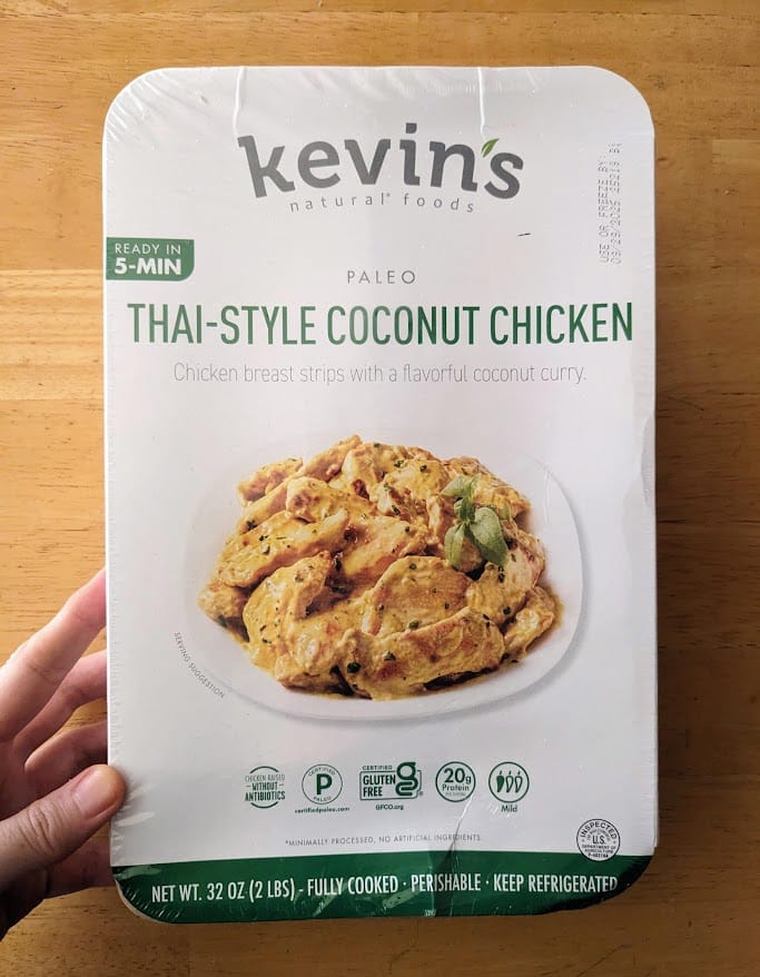 A hand holding a package of Kevin's Thai-Style Coconut Chicken Curry from Costco.