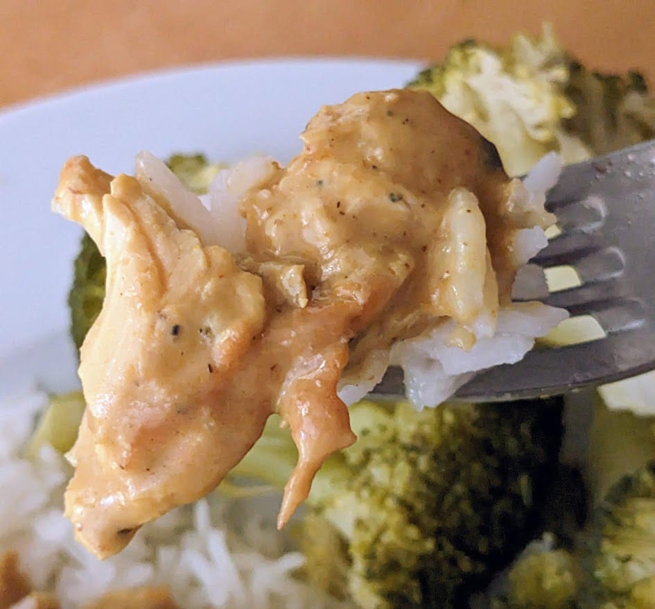 A fork with a bite of Kevin's Thai Curry Coconut Chicken meal with rice and broccoli.