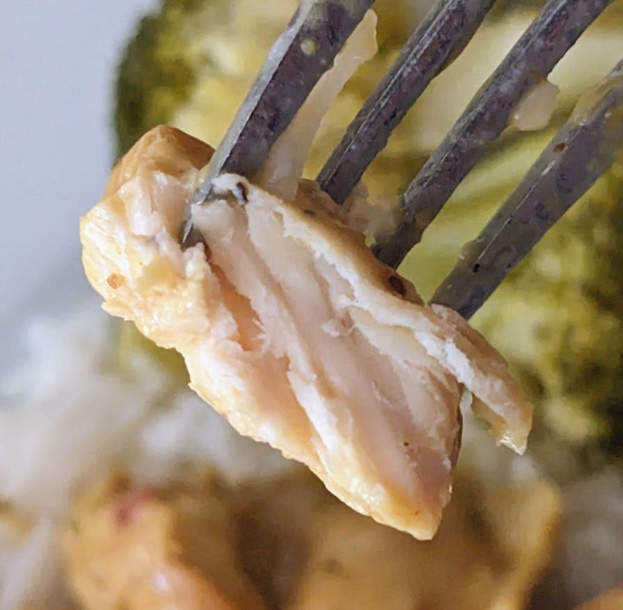 A fork holding a bite of meat from Kevin's Thai-Style Coconut Chicken curry meal.
