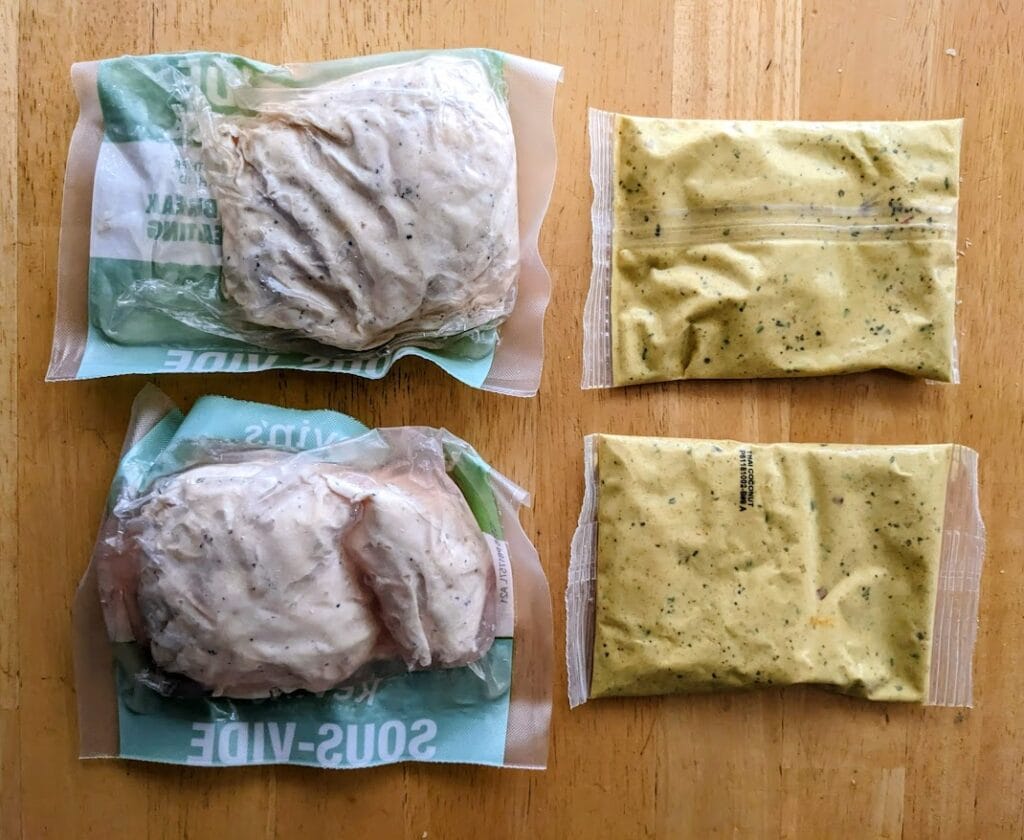 Plastic pouches of sous vide breast meat and sauce from a box of Kevin's Thai-Style Coconut Chicken curry meal.