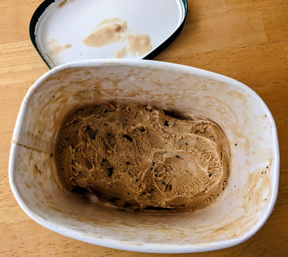 An open, mostly eaten tub of Publix Santa's White Christmas Ice Cream.