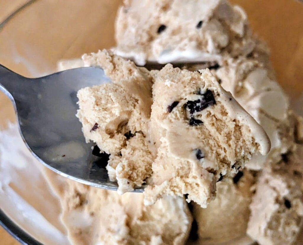 A spoon with a bite of Publix Santa's White Christmas ice cream, showing coffee color and chocolate flakes.