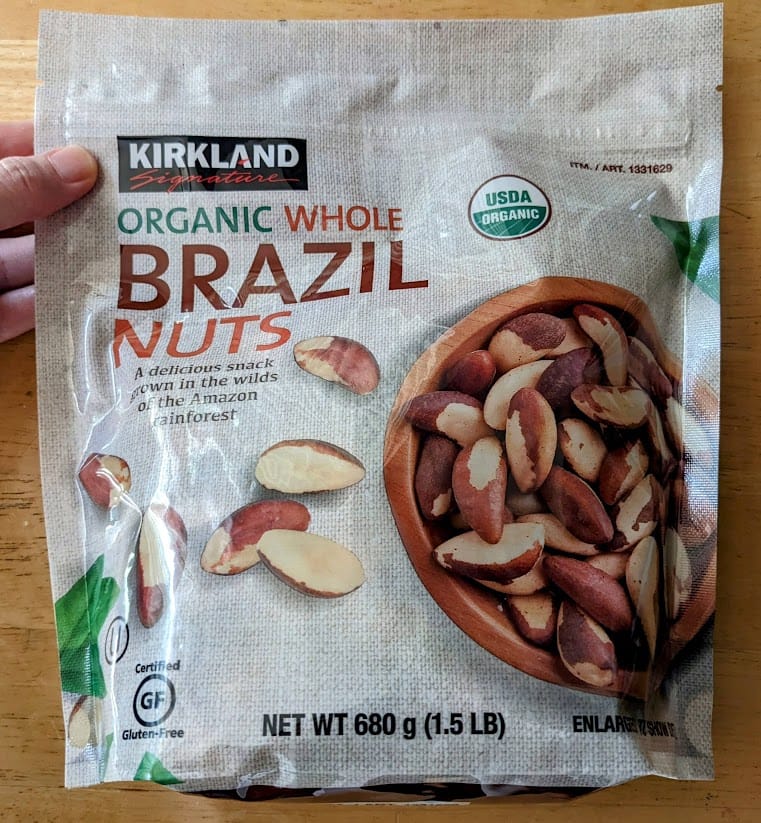 A hand holding a bag of Kirkland Organic Brazil Nuts from Costco.