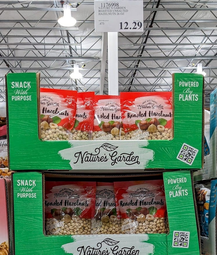 A stack of cartons inside a Costco warehouse with bags of Nature's Garden roasted hazelnuts.