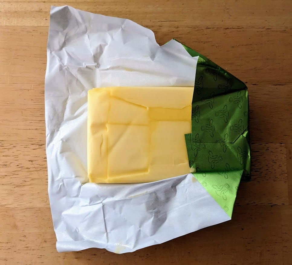 An unwrapped block of Kirkland Grass Fed New Zealand Butter from Costco, sitting on a kitchen table.