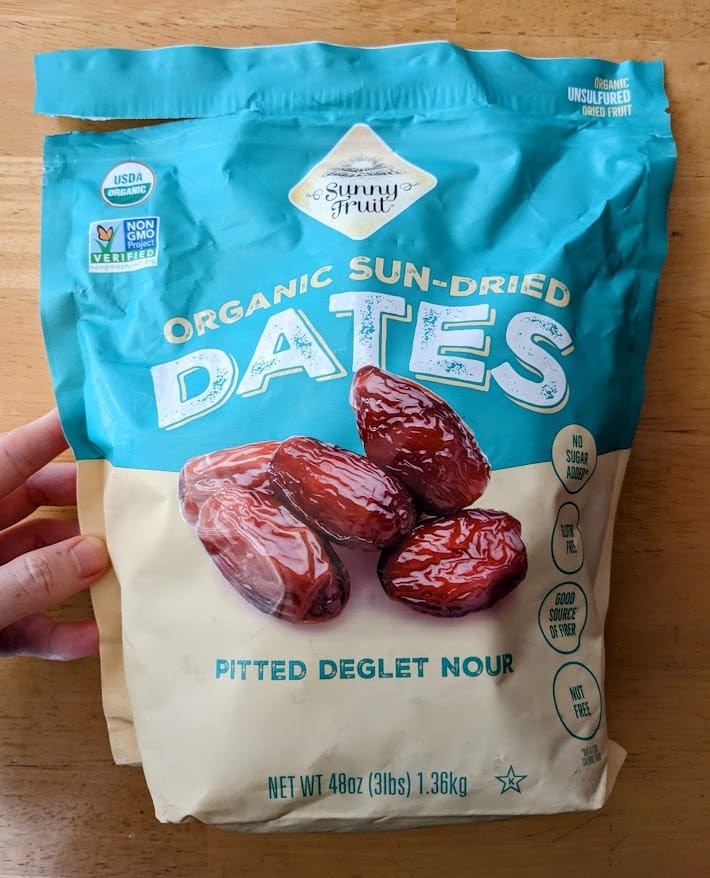 A hand holding a bag of Sunny Fruit Organic Dried Dates from Costco.