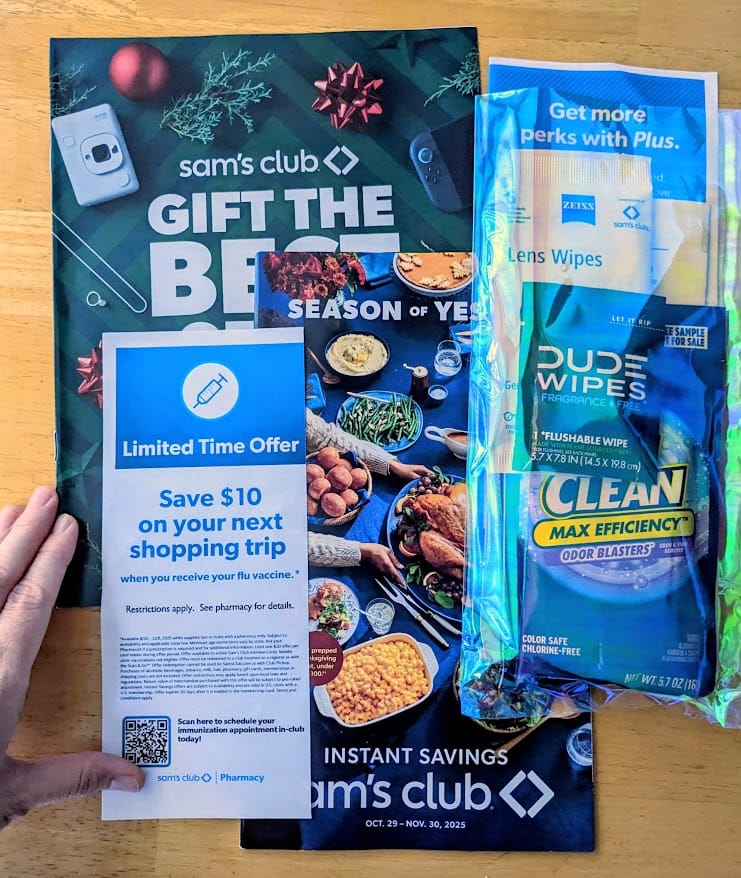 A hand next to assorted promotional literature from Sam's Club.