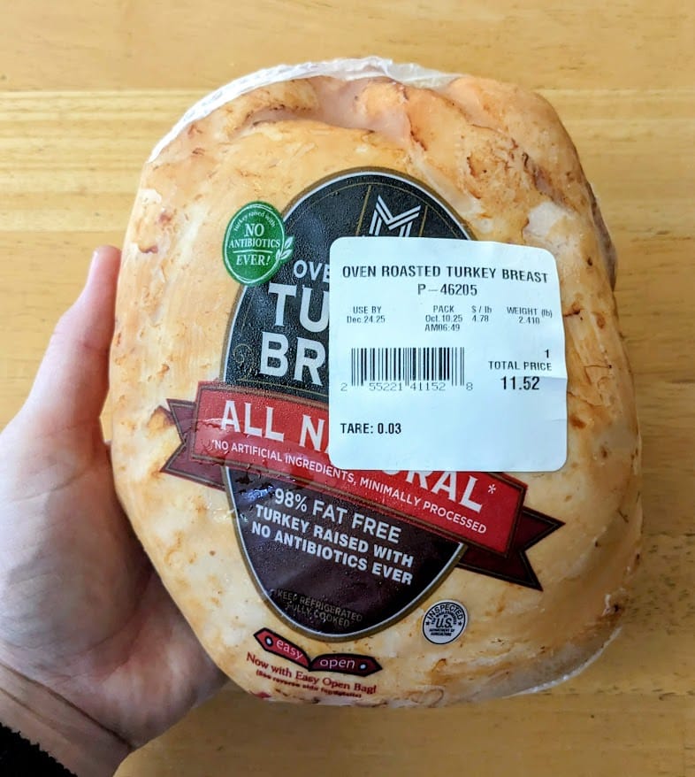 A hand holding a Member's Mark Oven Roasted Turkey Breast.