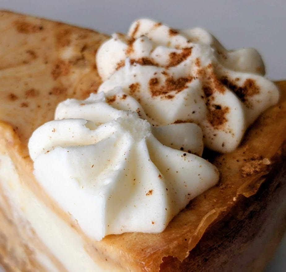 Piped garnishes on top of a slice of Sam's Club Pumpkin Cheesecake from Member's Mark store brand.