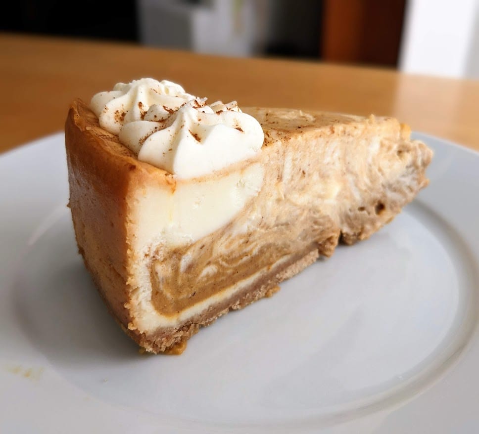 A slice of Member's Mark Pumpkin Cheesecake from Sam's Club, sitting on a white plate.