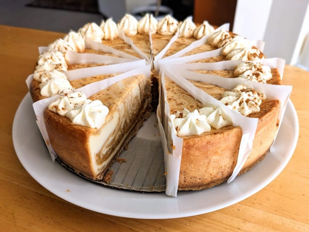 Slices of Sam's Club Pumpkin Cheesecake divided by wax paper on a plate.