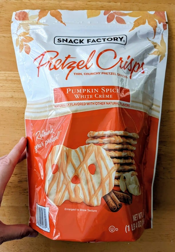 A hand holding a bag of Snack Factory Pumpkin Spice Pretzel Thins.