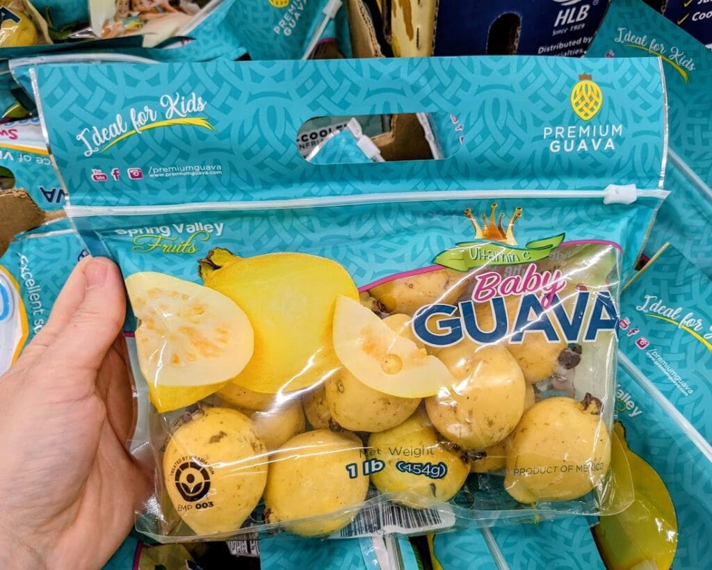 A hand holding a bag of baby guava fruits.