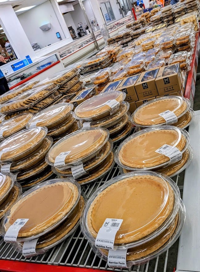 A long table inside a Sam's Club Bakery with pies, cookies, and cakes.