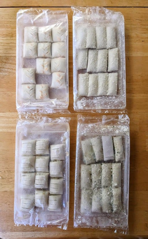 Four sealed plastic trays with frozen puff pastry bite appetizers from Cuisine Adventures.