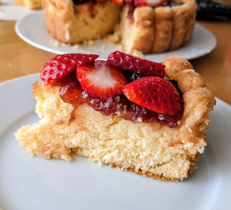 A slice of Aldi Yellow Cake topped with fresh strawberries and jam.
