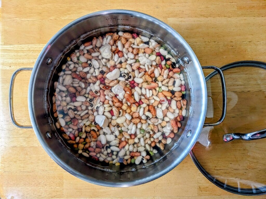 A large pot with dry beans soaking in water.