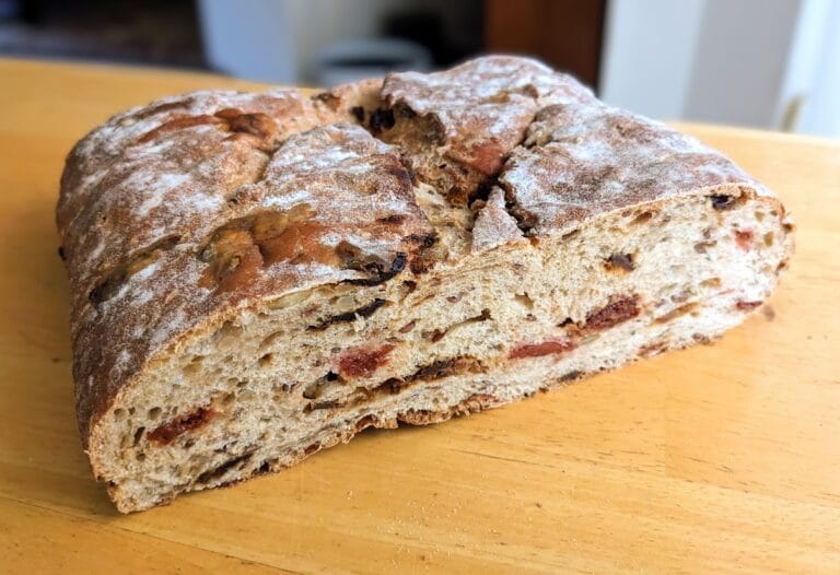 A sliced loaf of Costco Cherry & Fig Bread, sitting on a kitchen table.