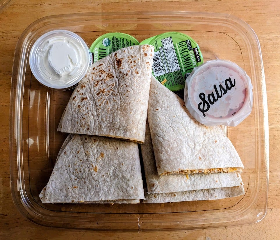 Open package of Chicken Quesadilla Meal Kit from the Costco Deli, with four cups of dipping sauce.
