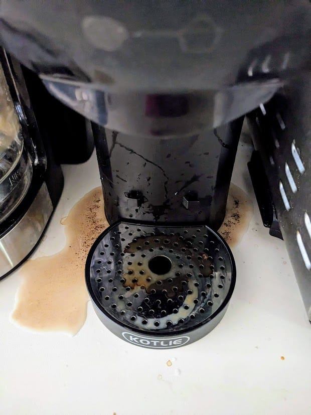 A Kotlie espresso machine with coffee and grounds leaking out onto a countertop.