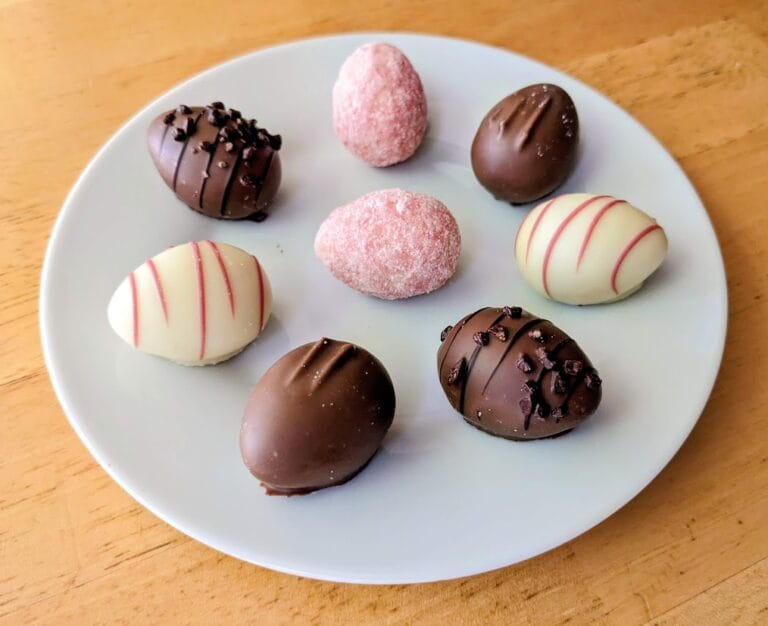 A small white plate with pink, white, and brown chocolate truffle Easter eggs from Aldi.