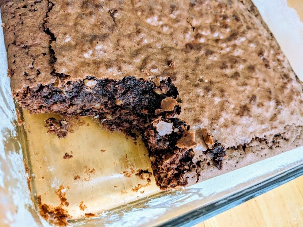 A glass pan with prepared brownies made from an Aldi Chewy Fudge mix.