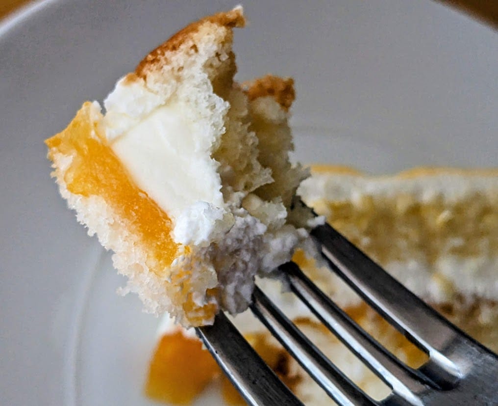 A fork with a bite of Costco Peaches and Cream Bar Cake, showing the layers and filling.