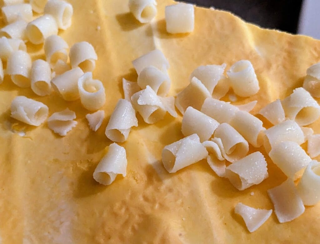 White chocolate curls garnish on top of an orange Peaches and Cream bar cake from Costco.