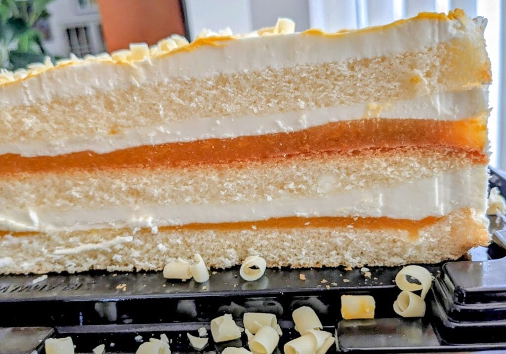 Cross section of a Costco Peaches and Cream Bar Cake, showing filling and whipped topping.