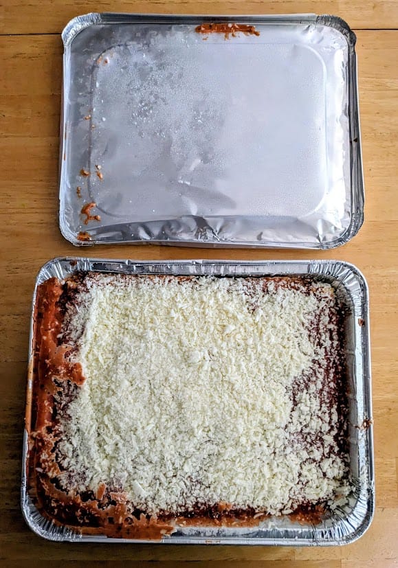 An aluminum pan with frozen Bremer lasagna from Aldi with the lid removed.